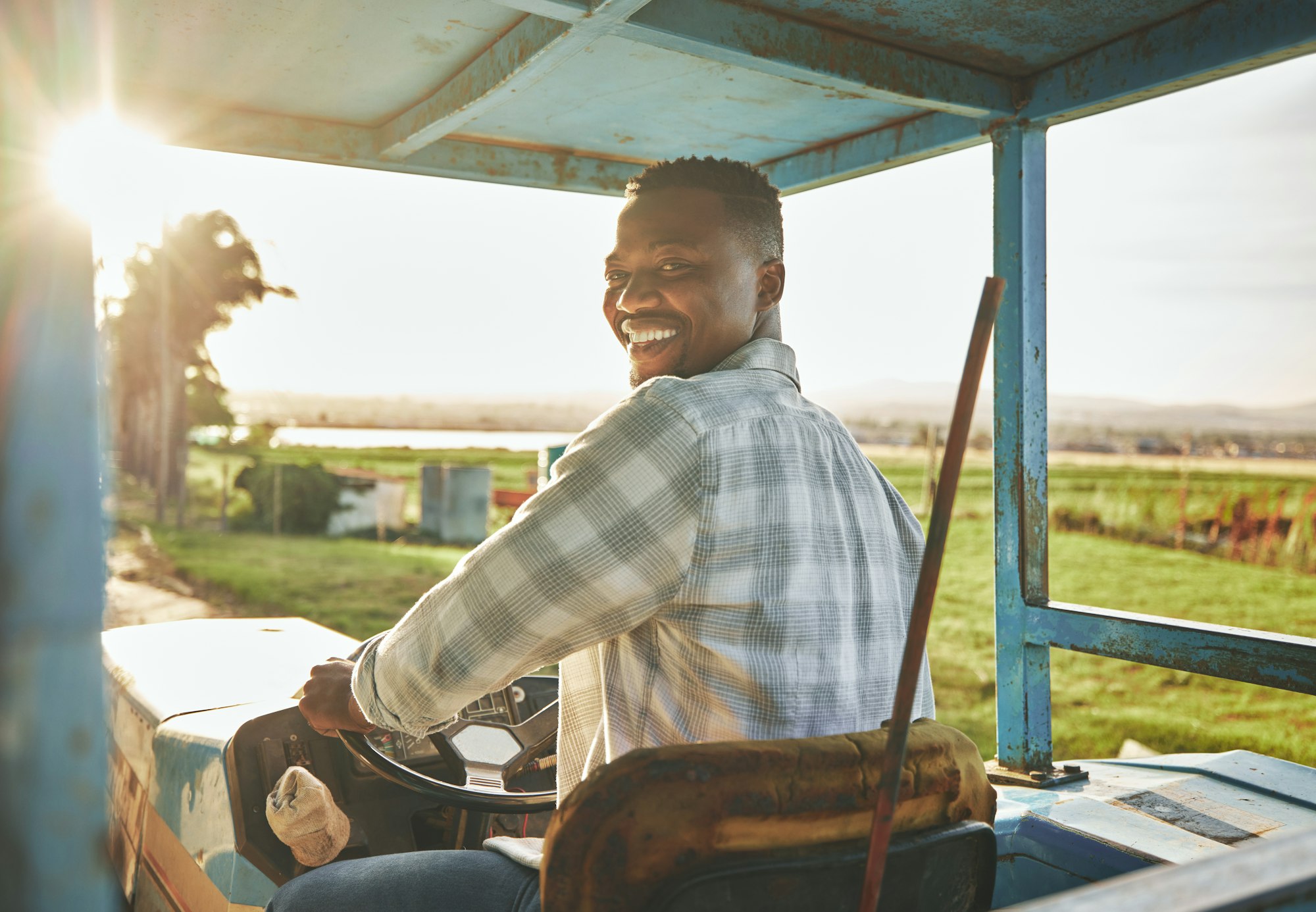 Green fingers. Shot of a young farmer driving a tractor on a farm.